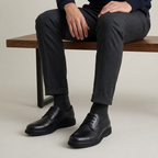 Chaussures Avanda noires portées par un homme assis sur un banc en bois